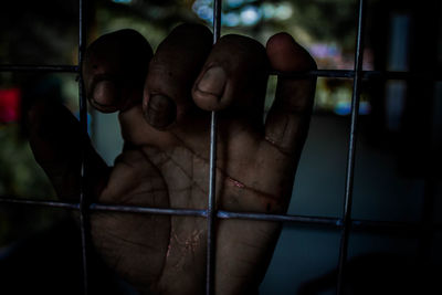 Close-up of person hand on metal grate in building