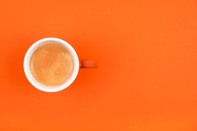 Directly above shot of coffee cup against orange background