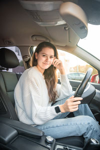 Portrait of young woman sitting in car