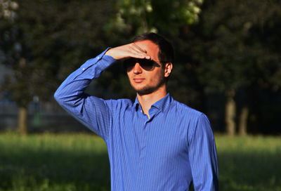 Young man shielding eyes on sunny day