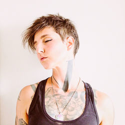 Portrait of young woman standing against white background