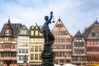 Low angle view of statue against building in city against sky