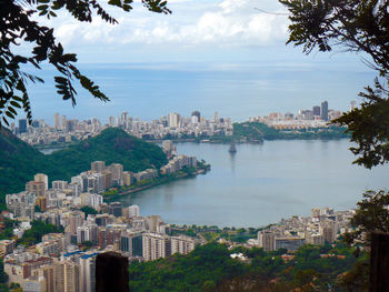 City at waterfront against cloudy sky