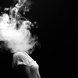 Close-up of man smoking against black background