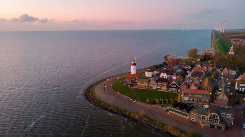 High angle view of city by sea against sky during sunset