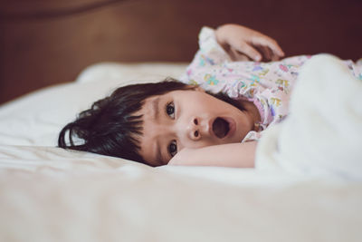 Girl yawning while lying on bed at home