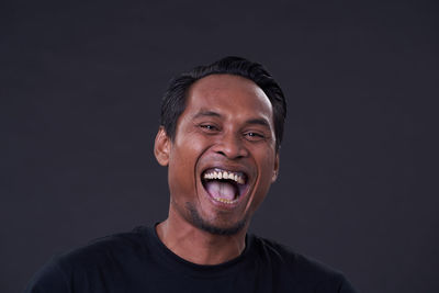 Portrait of smiling man against black background