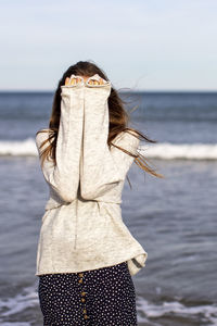 Portrait of woman standing at beach against sky