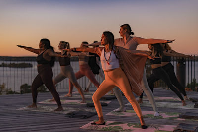 Women practicing yoga together while standing on patio at retreat center