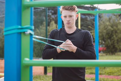 Fitness trainer exercises the upper half of the body on an outdoor court with the help of expander