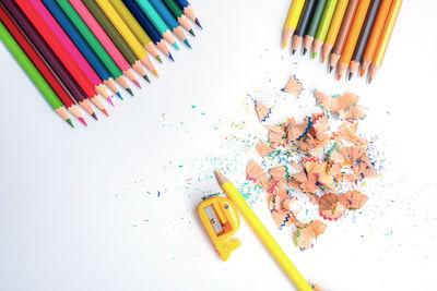 High angle view of colored pencils against white background