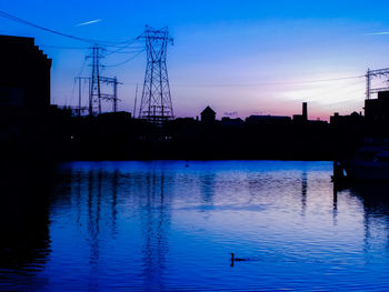 Silhouette of electricity pylon at sunset