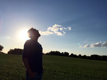 People standing on grassy field at sunset