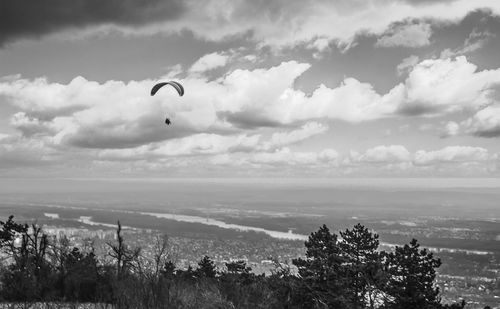 Bird flying over sea against cloudy sky