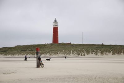 Lighthouse on beach against sky