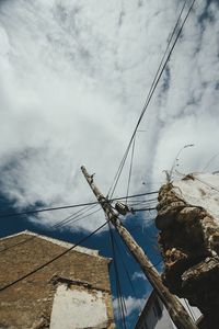 Low angle view of power lines against cloudy sky