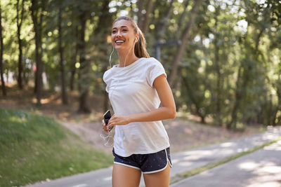 Smiling young woman standing against trees