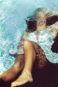 Low section of woman relaxing in swimming pool