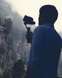 Rear view of man photographing through mobile phone during winter season