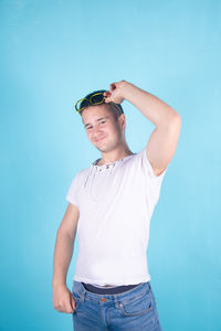 Portrait of young man standing against blue background