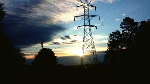 Low angle view of electricity pylon against cloudy sky