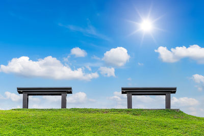 Park bench on field against sky