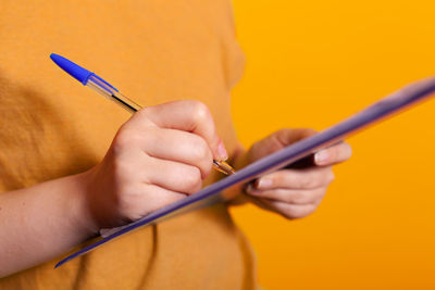 Cropped hand of woman writing on paper