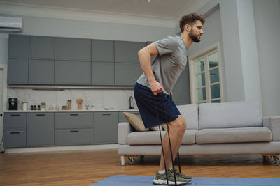 Full length of young woman exercising at home