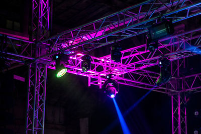 Low angle view of illuminated lighting equipment hanging at night