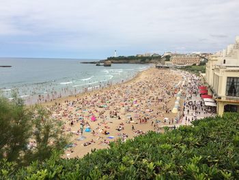 High angle view of people at beach against cloudy sky