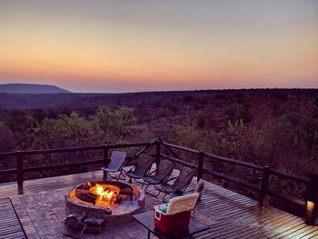 High angle view of fire by chairs against landscape and sky during sunset