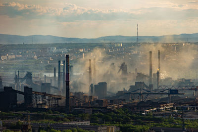 Smoke emitting from factory against sky