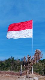 Red flag on built structure against blue sky