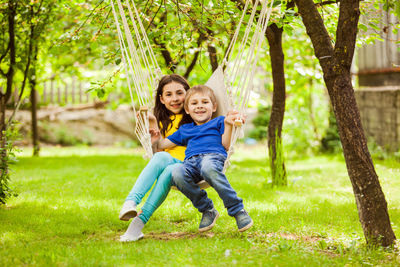 Boy and girl sitting on hammock in park