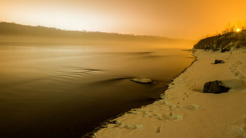 Scenic view of lake against sky at sunset