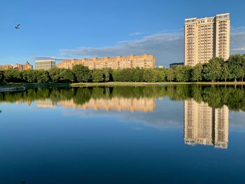 Reflection of buildings in lake against blue sky