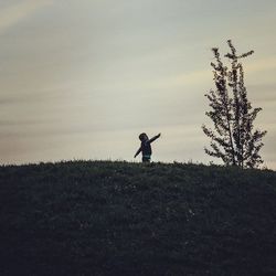 People standing on field at sunset