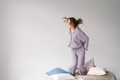 Side view of young woman standing against white background