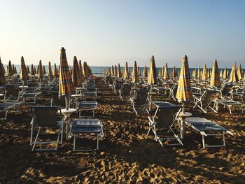 Parasols and lounge chairs at beach against clear sky