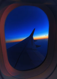 Airplane wing against clear blue sky seen through window