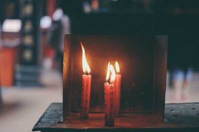 Burning candles by metal on table