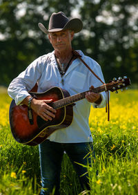 Midsection of man playing guitar on field