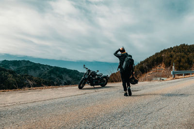 Man riding motorcycle on road against sky