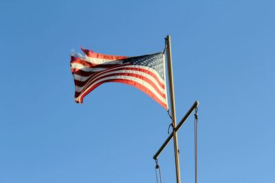 Low angle view of flag against clear blue sky