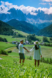 Rear view of people on field against mountains