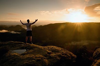 Runner on the peak gesture triumph with hands in the air. crazy man in black pants and white t-shirt