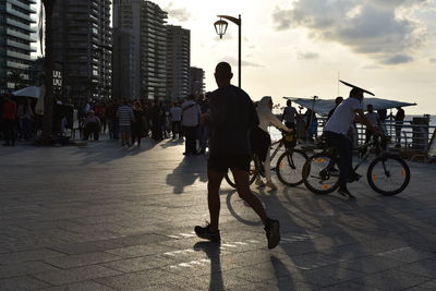 People riding bicycle and jogging on street in city