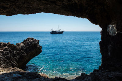 Pirate ship sailing in the sea. view from inside a cave