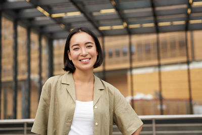 Portrait of young woman standing against wall