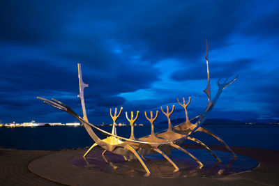 Dead tree on beach against sky at dusk